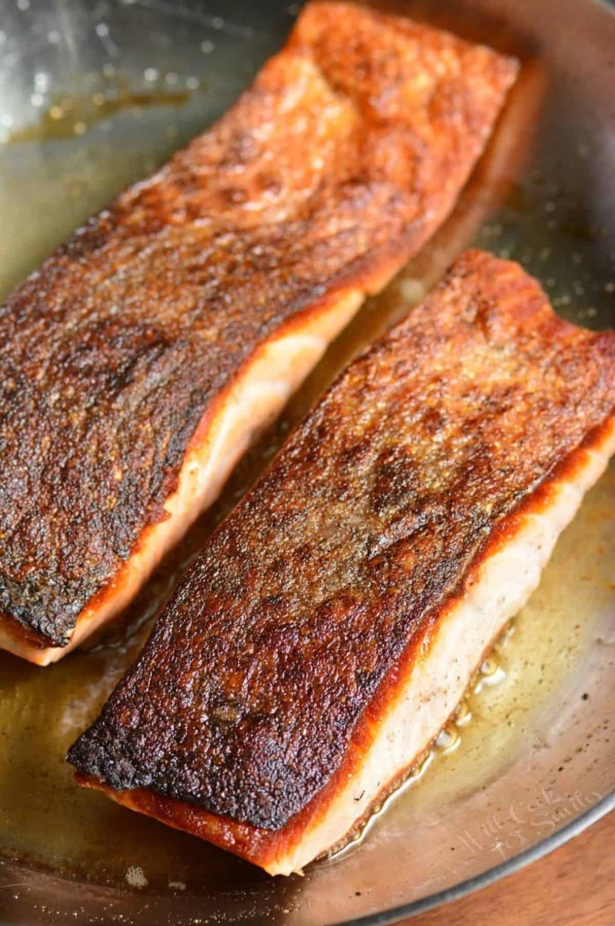 two salmon filets with crispy skin in the metal pan.