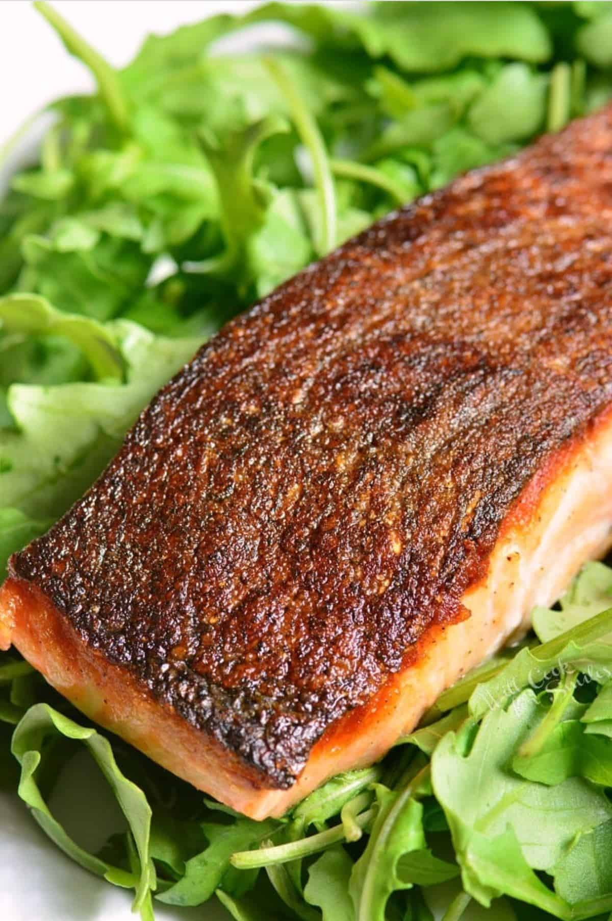 crispy skin salmon skin up on a bed of greens.