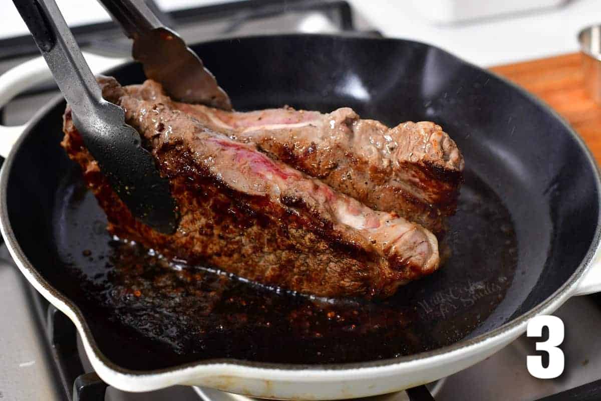 holding with tongs and searing sides of steaks in a cast iron pan.