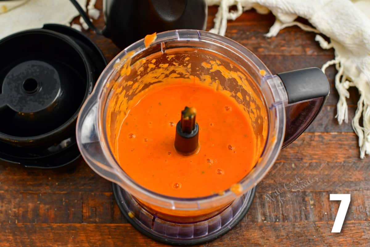 blended red tomato sauce in a blender with lid next to it.