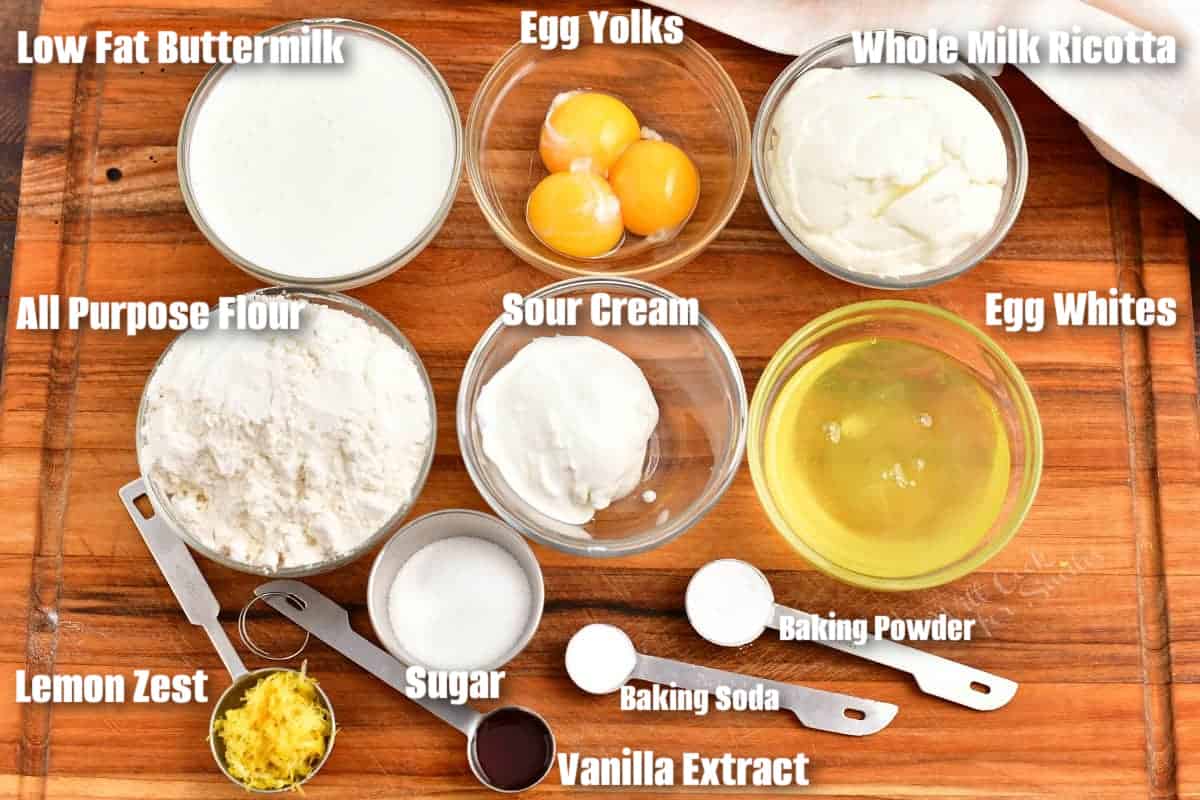 labeled ingredients to make ricotta pancakes on a wooden cutting board.