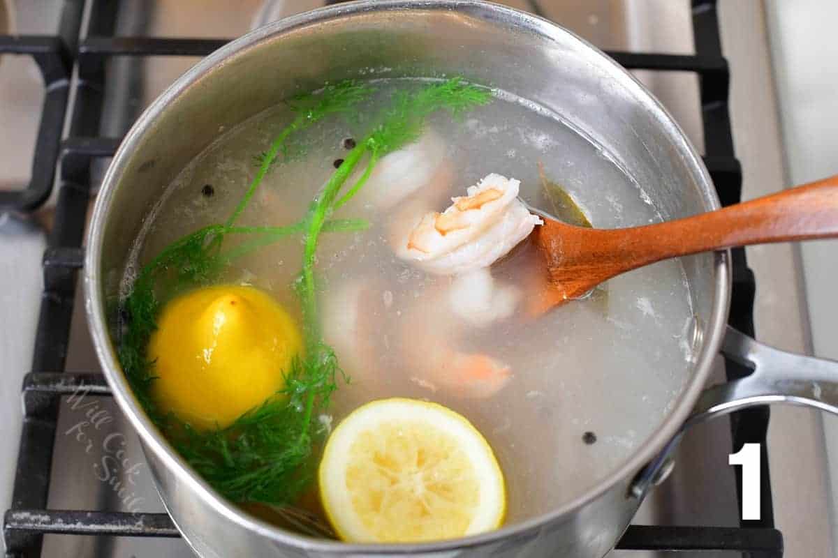 shrimp, lemon, and herbs cooking in a silver pot.