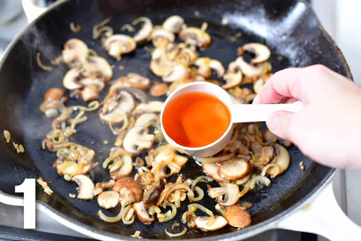 adding cognac to the mushrooms and onions in the pan.