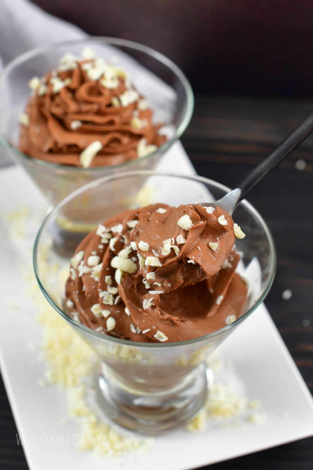 scooping out chocolate mousse with a dessert school from a clear glass.