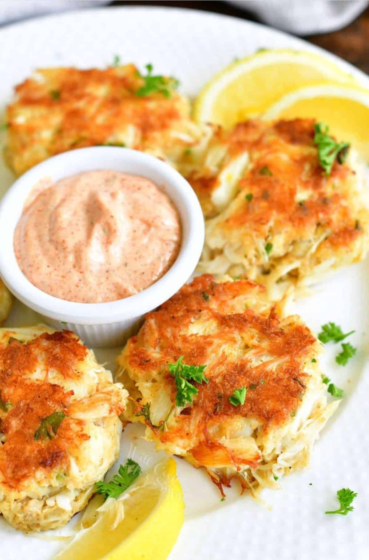 four cupcakes visible on the white plate with remoulade sauce and lemon wedges.