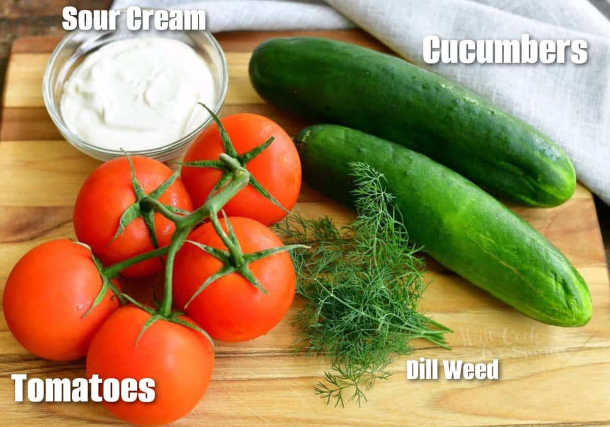 labeled ingredients for cucumber tomato salad on cutting board.