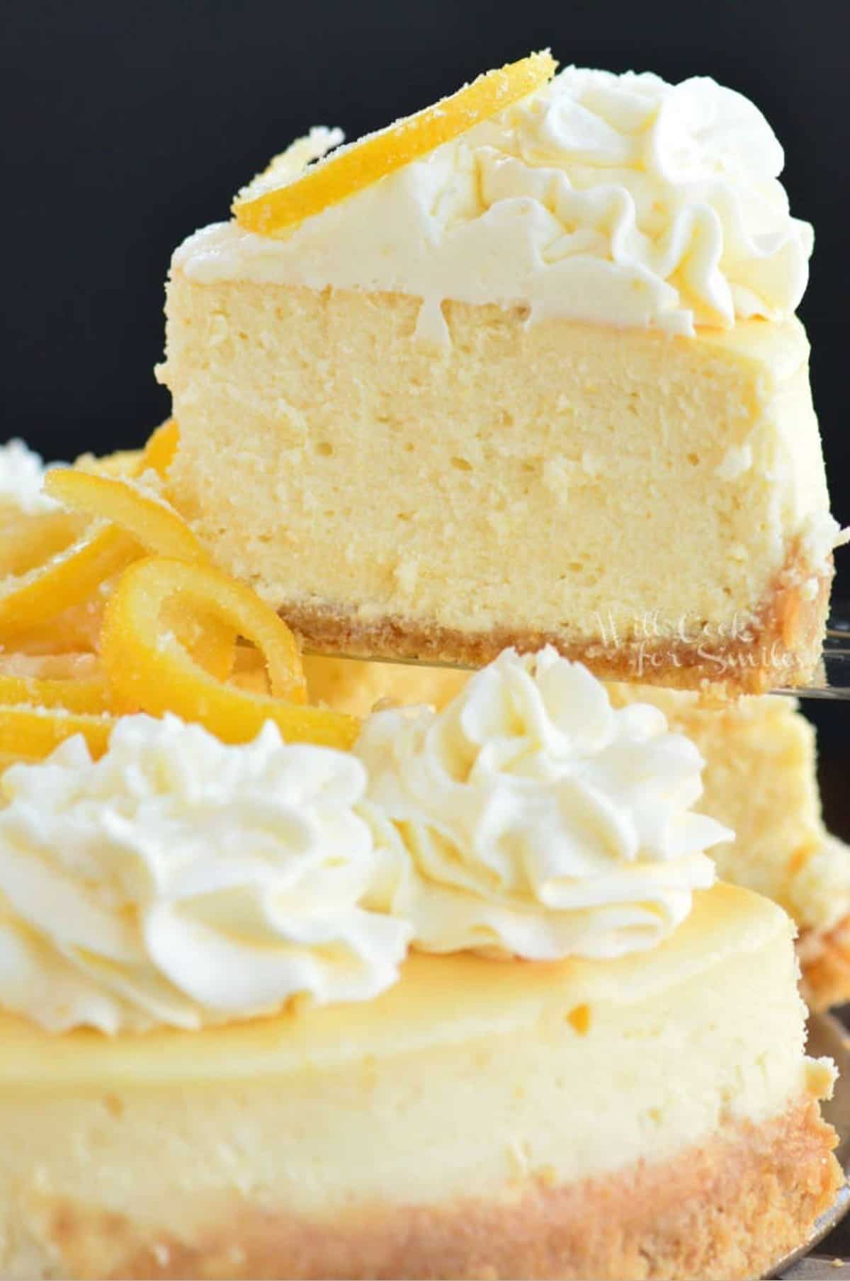 pulling out a slice of lemon cheesecake from the whole cheesecake.
