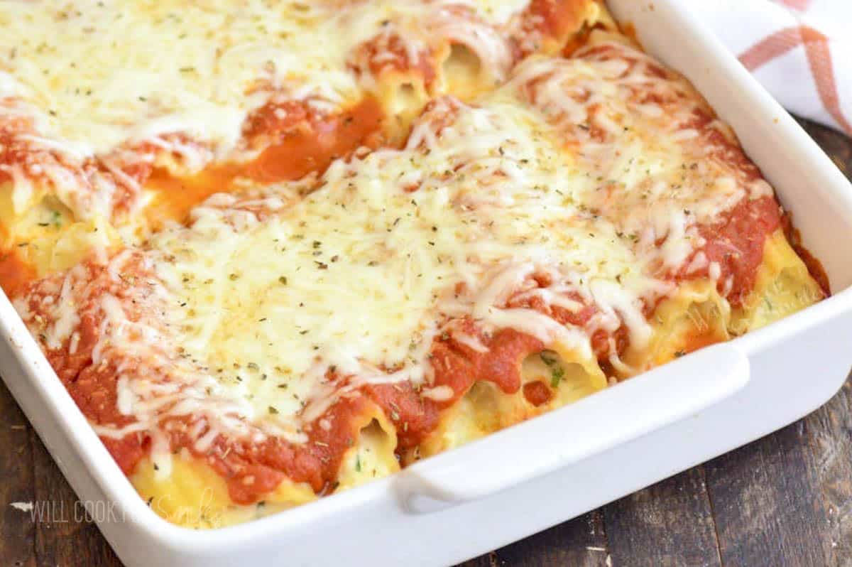 baked manicotti in a white baking dish topped with some dried oregano.