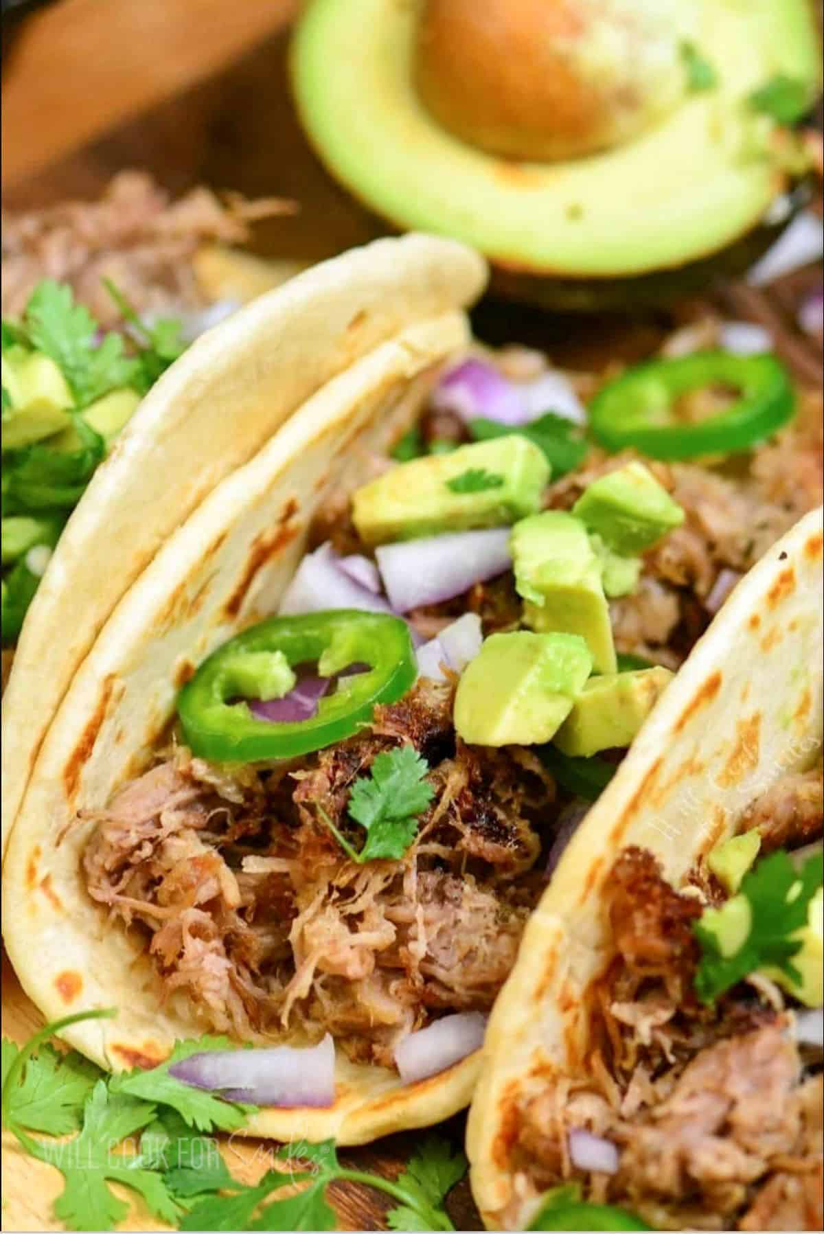 pork carnitas taco topped with avocado, onion, and jalapenos.