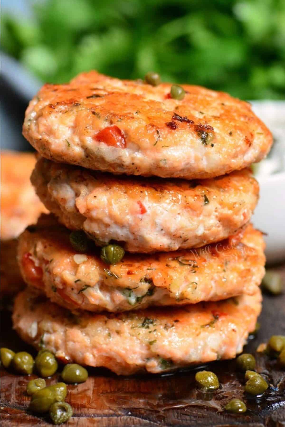 stack of four salmon patties with capers around and on top.