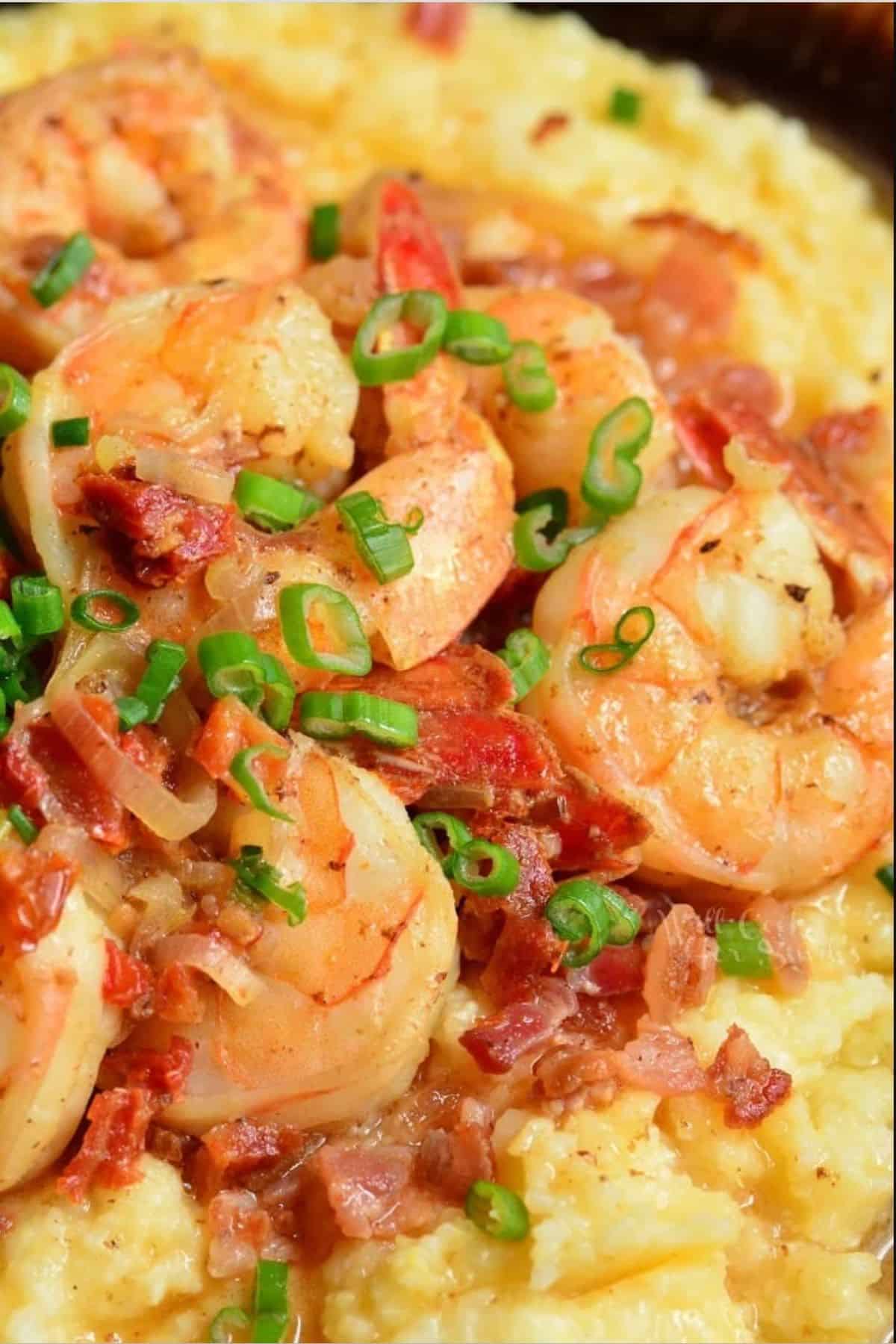 three large shrimp with bacon and tomatoes over the cheesy grits.