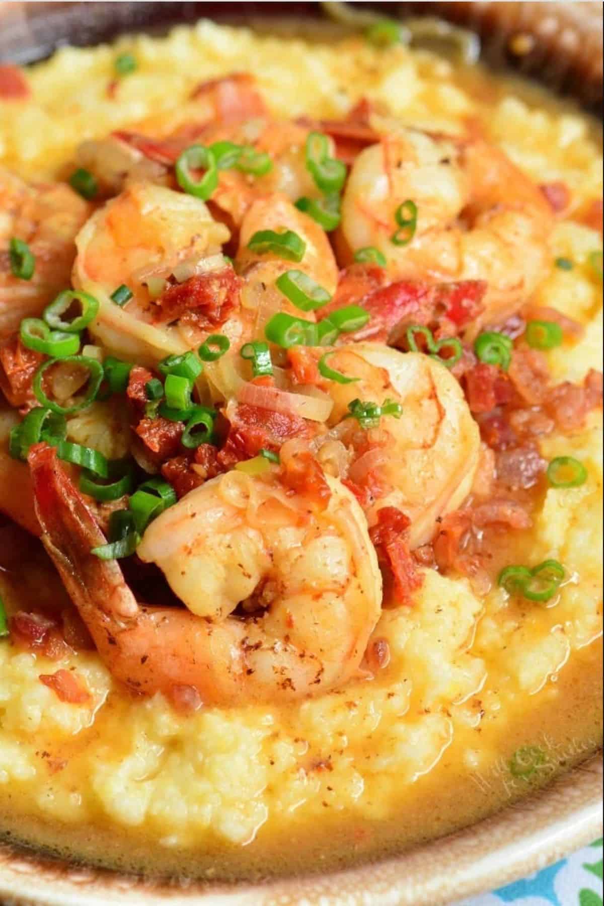 several large shrimp, tomatoes, and green onions with sauce over the grits.