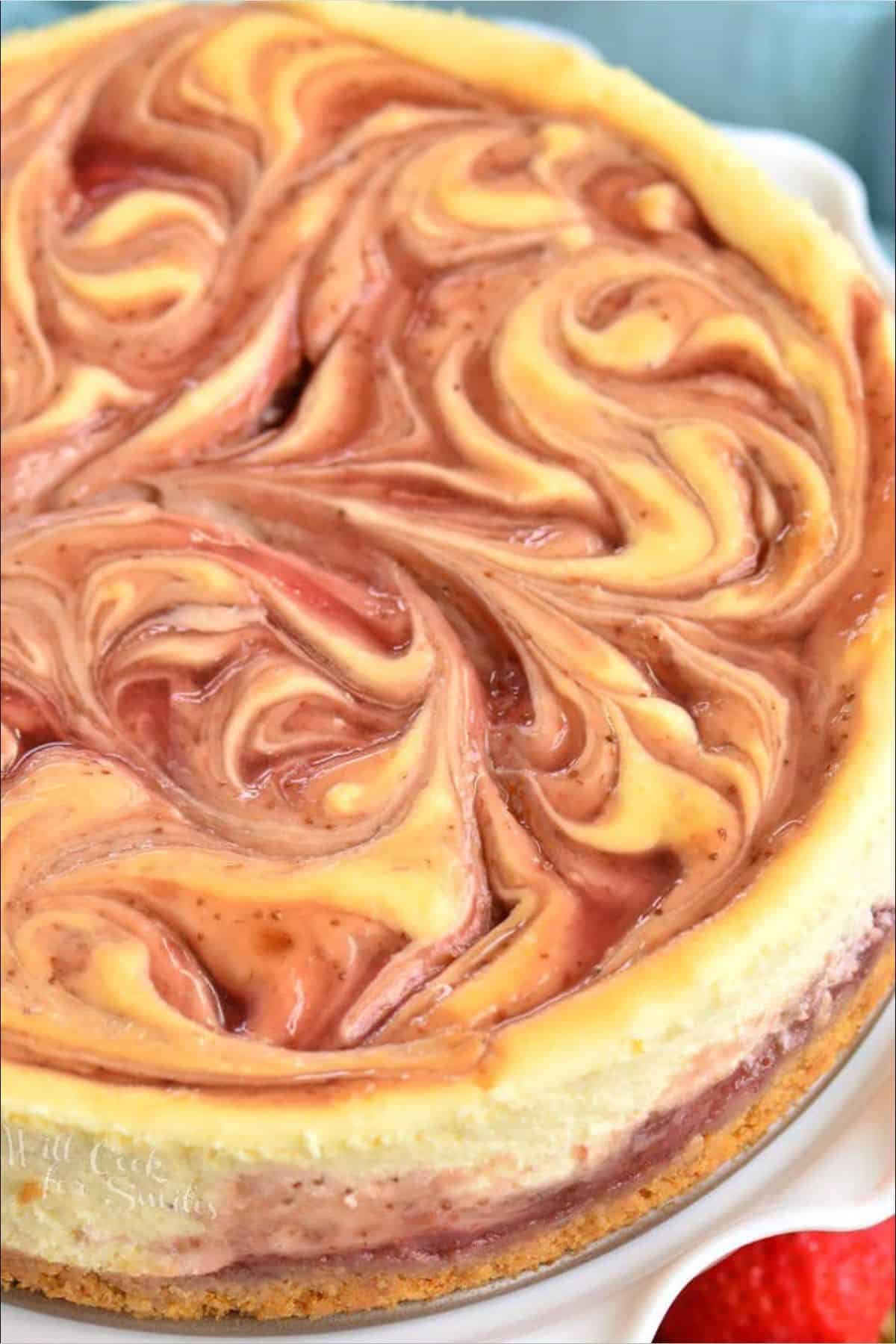 baked strawberry swirled cheesecake on the cake plate.