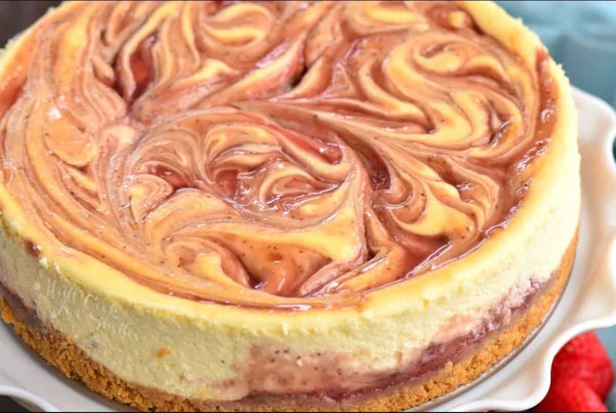 strawberry cheesecake with swirled strawberry sauce on the white plate.