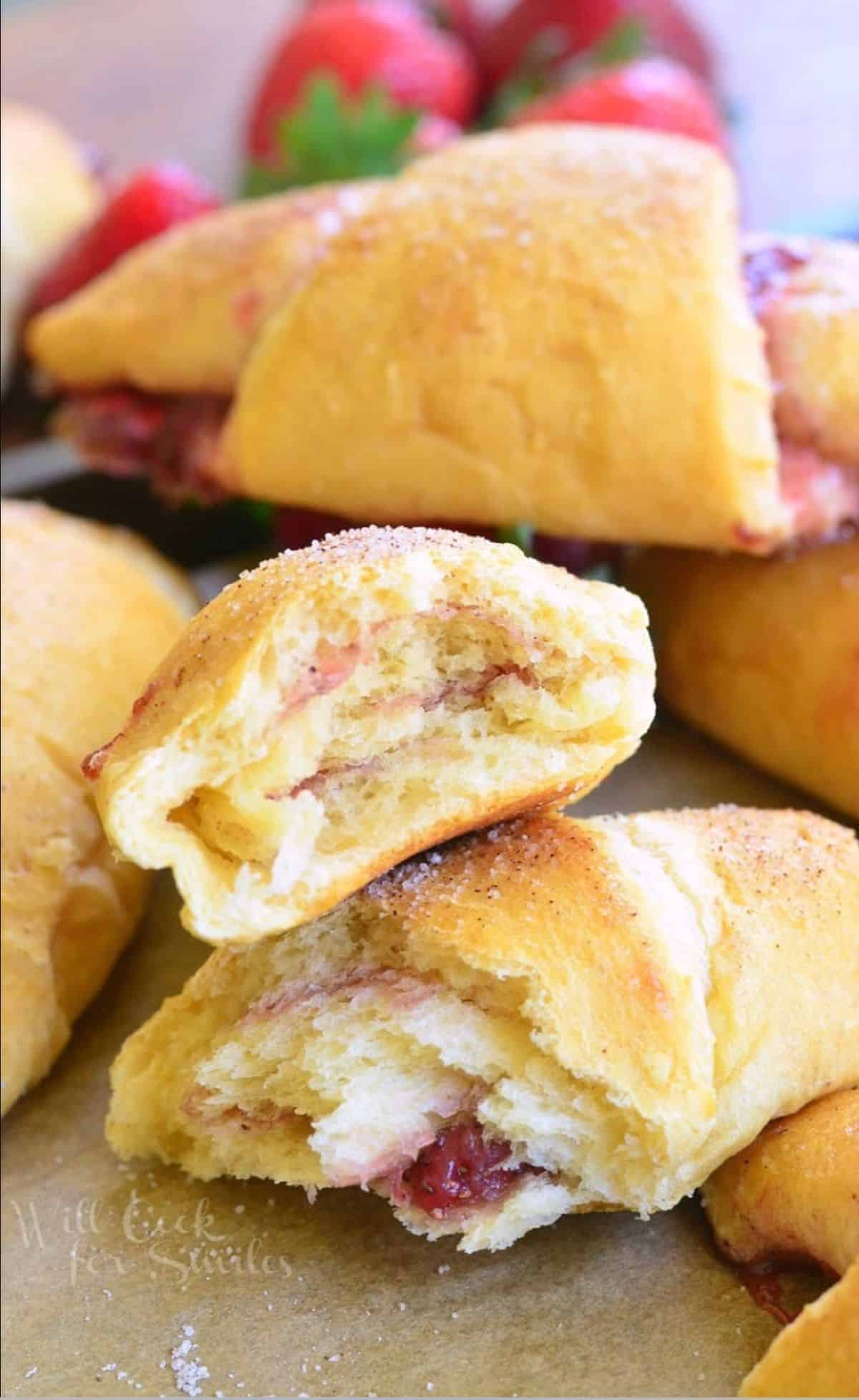 strawberry croissant rolls on a baking sheet tray with strawberries split in half.