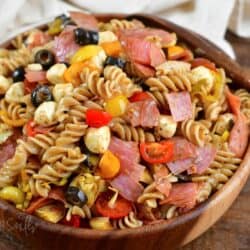 antipasto pasta salad in a wooden salad bowl with a wooden spoon.