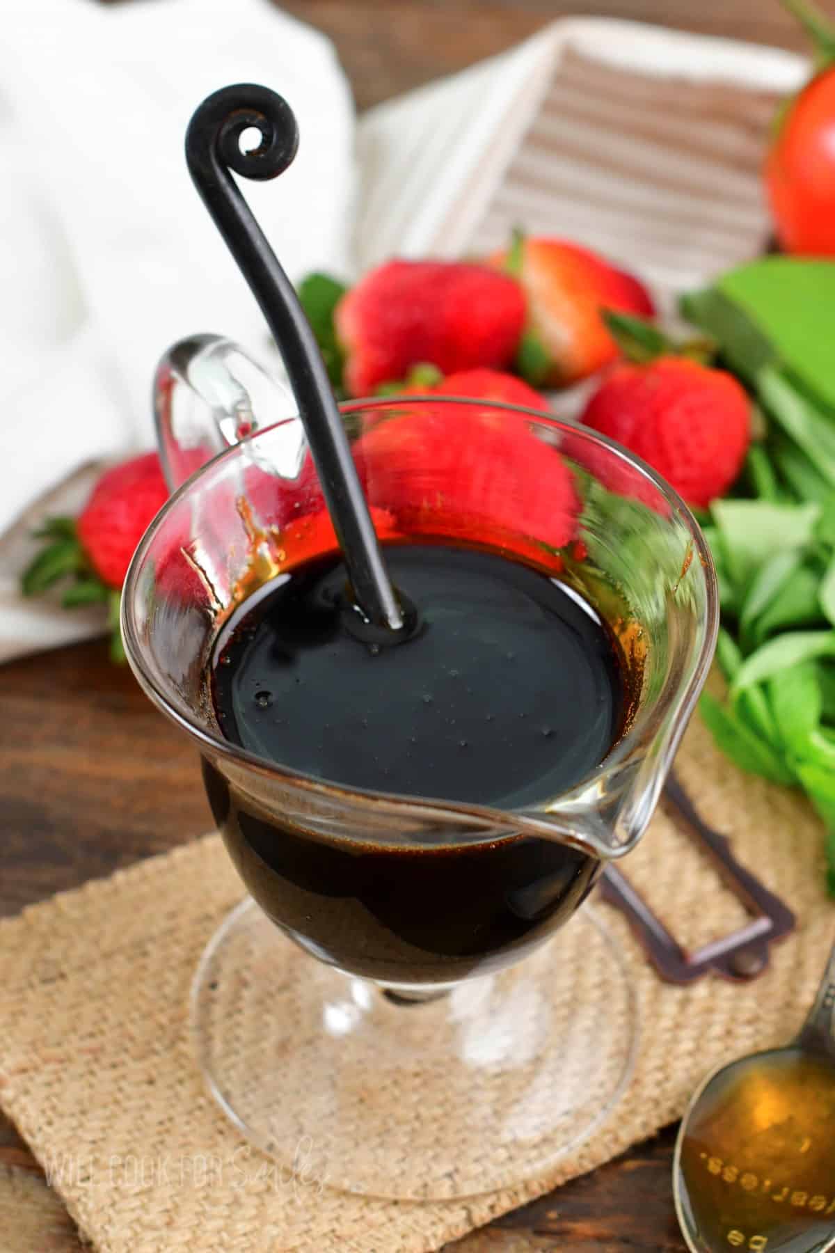 balsamic glaze in a glass sauce cup and spoon in it.
