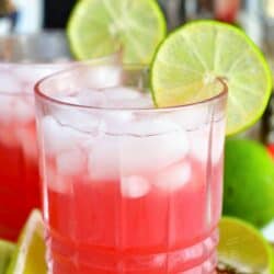 Pink Bay Breeze cocktail in the rocks glass with ice and a lime ring on the rim.