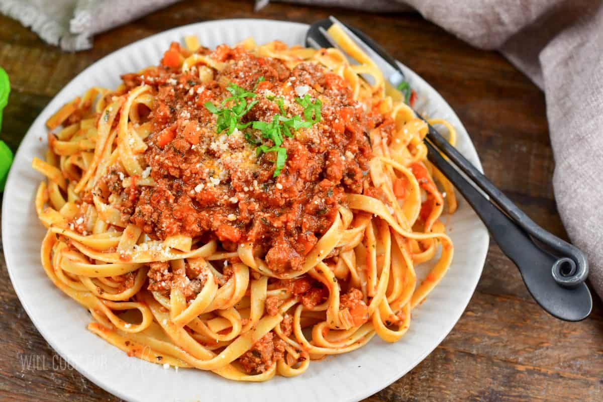 Fettuccine with Bolognese sauce topped with more sauce, parmesan, and basil.