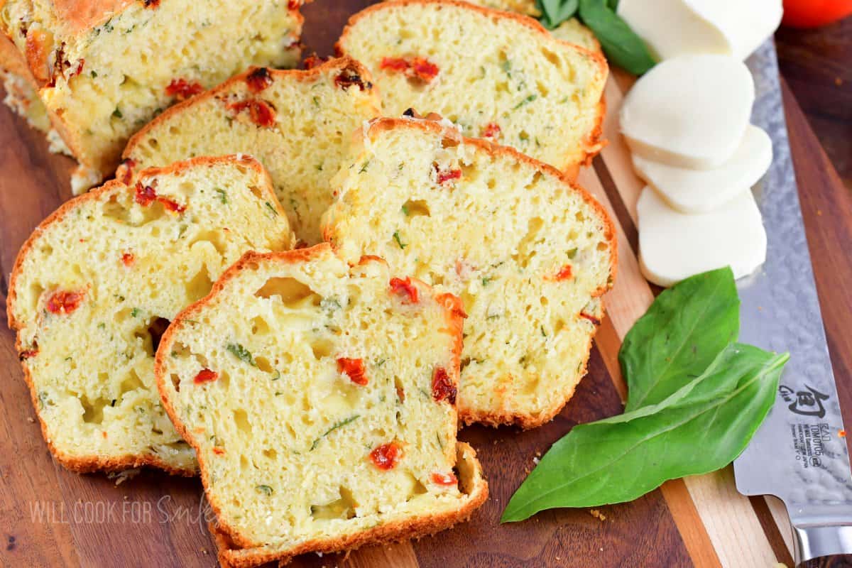 several slices of caprese bread next to each other with basil leaves and mozzarella slices.