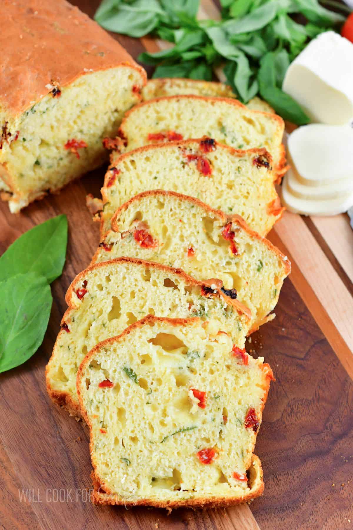 sliced caprese bread stacked next to each other on the cutting board.