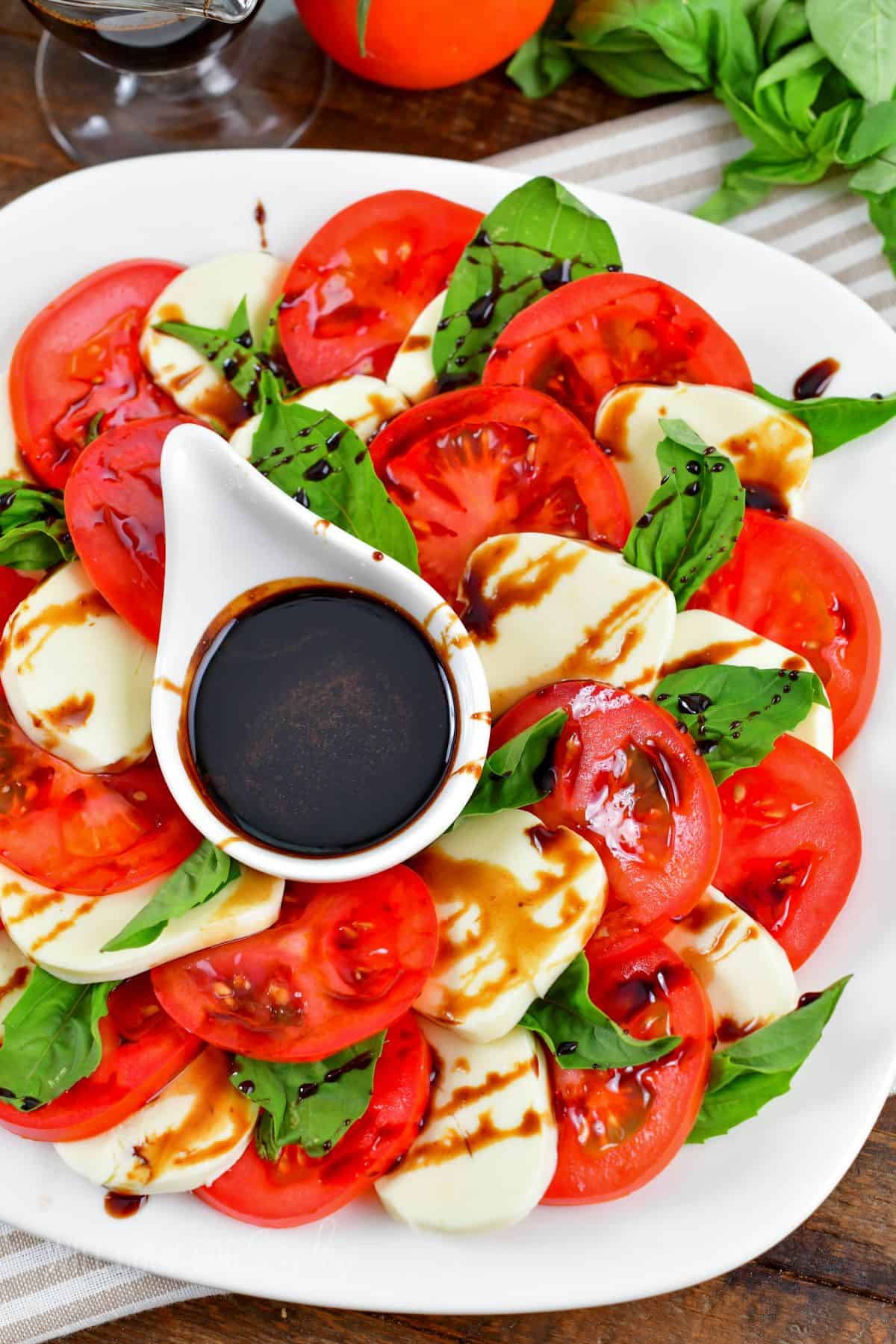 layered tomatoes and mozzarella cheese slices with basil leaves and balsamic reduction.