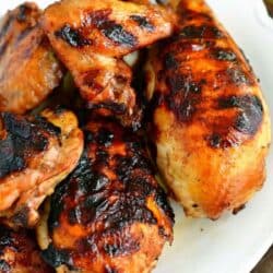 several pieces of grilled marinated chicken on the white plate.