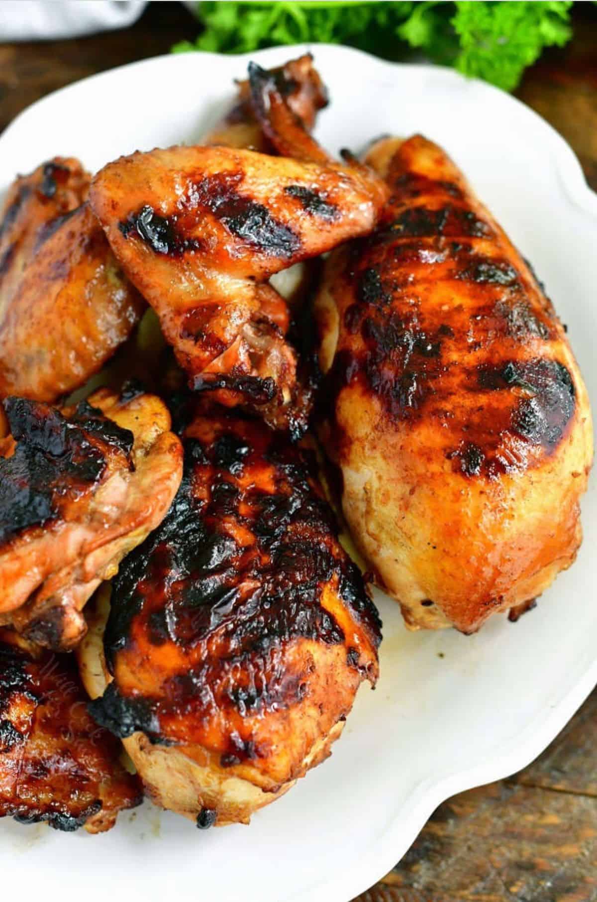 several pieces of grilled marinated chicken on the white plate.