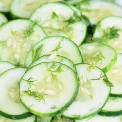 simple cucumber salad in a plate topped with dill weed.