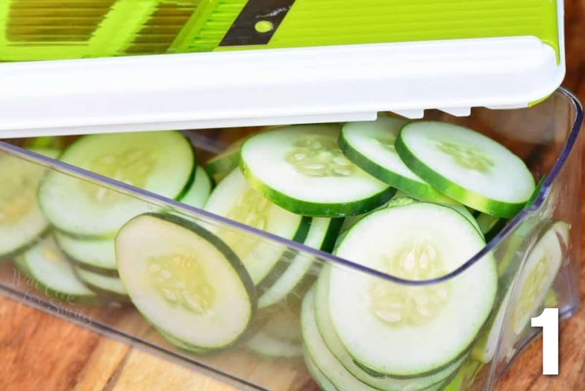 sliced cucumber in the container of the mandoline slicer.