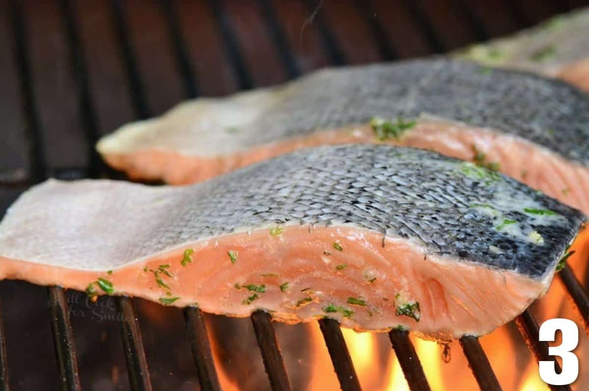 salmon filets cooking on the grill skin side up.