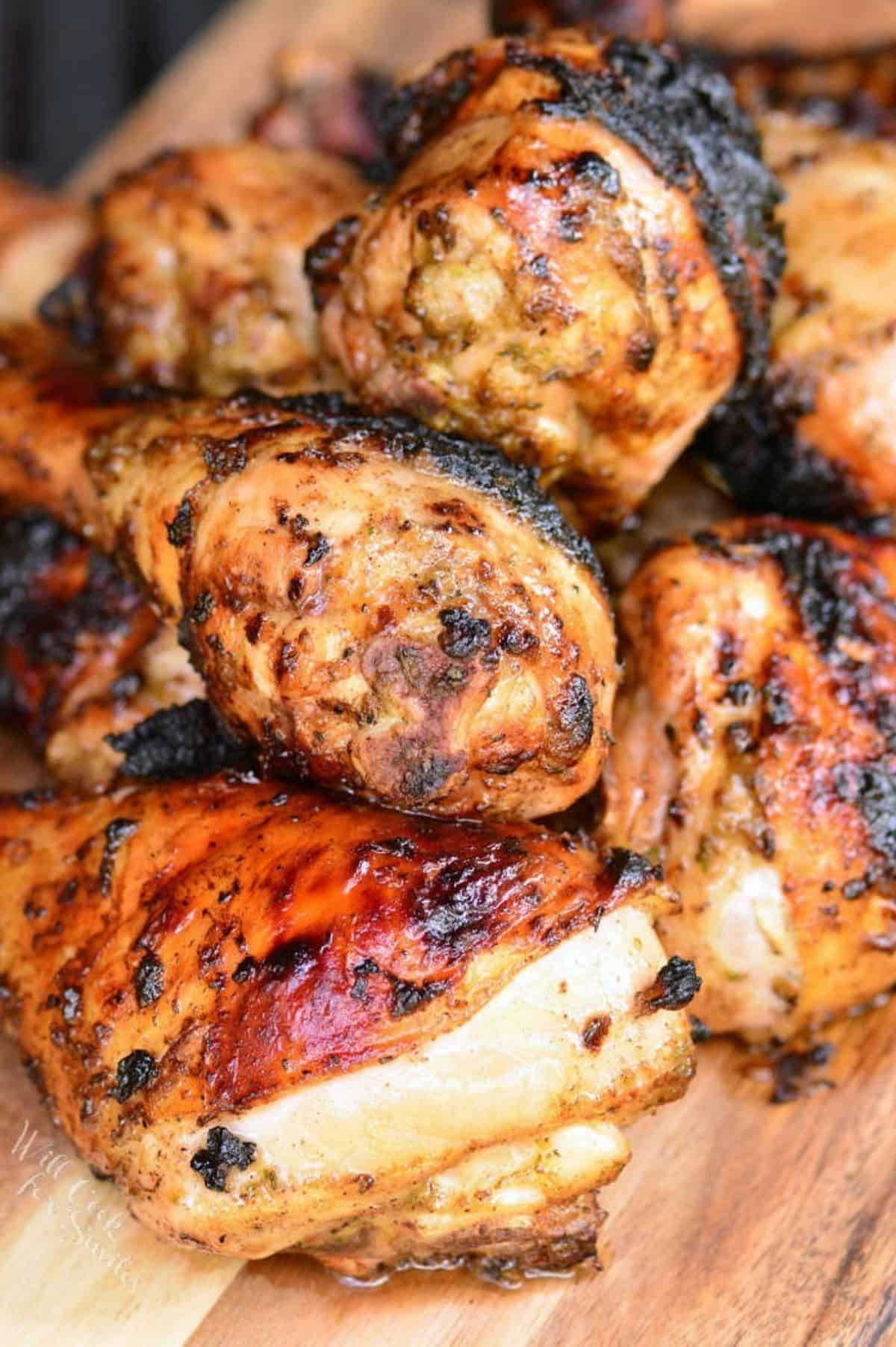 cooked jerk chicken drumstick stacked on the wooden plate.