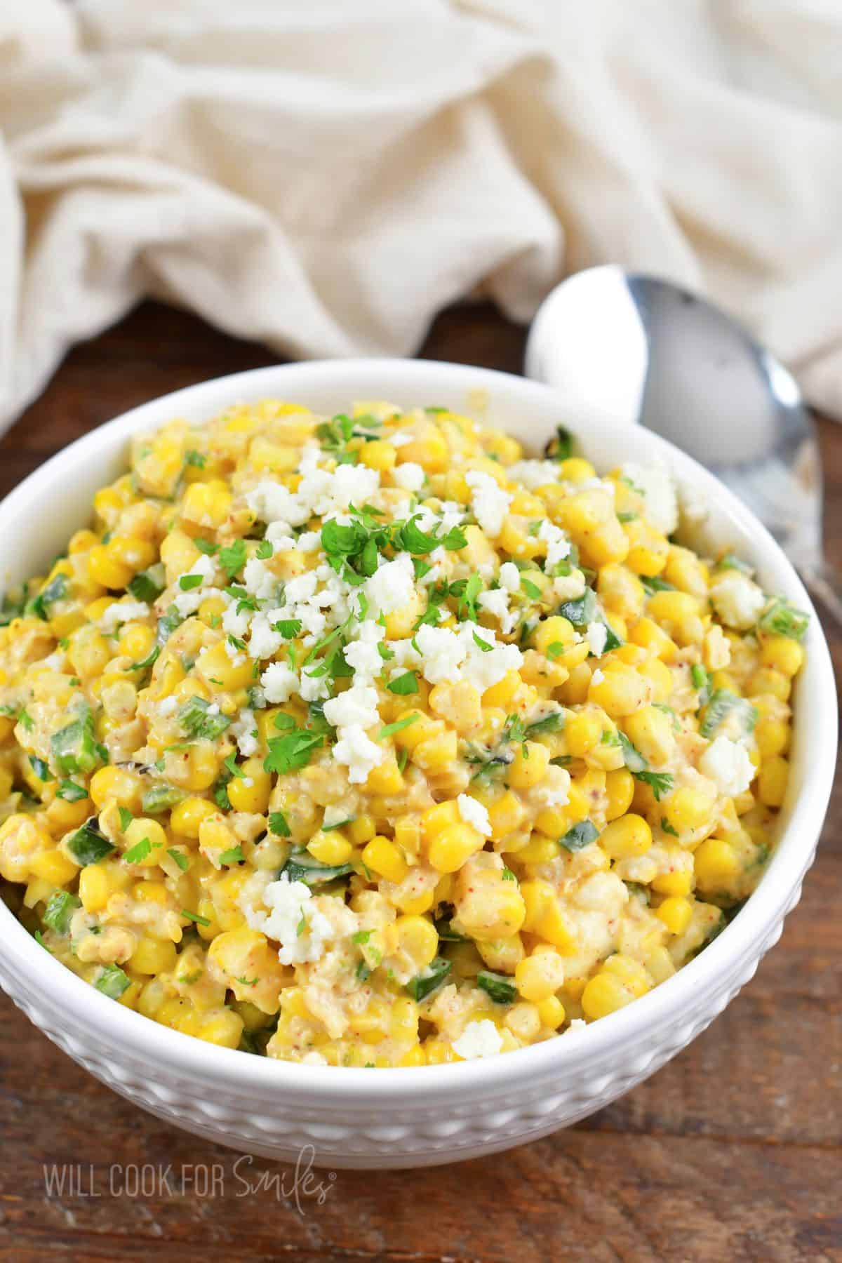creamy corn salad with queso and cilantro on top in a bowl.