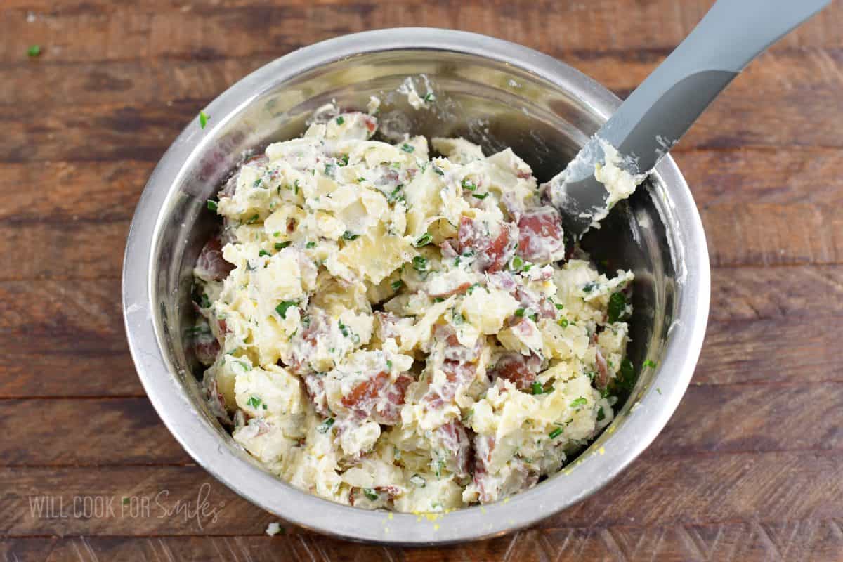 mixed parmesan potato salad in a mixing bowl with a spatula.