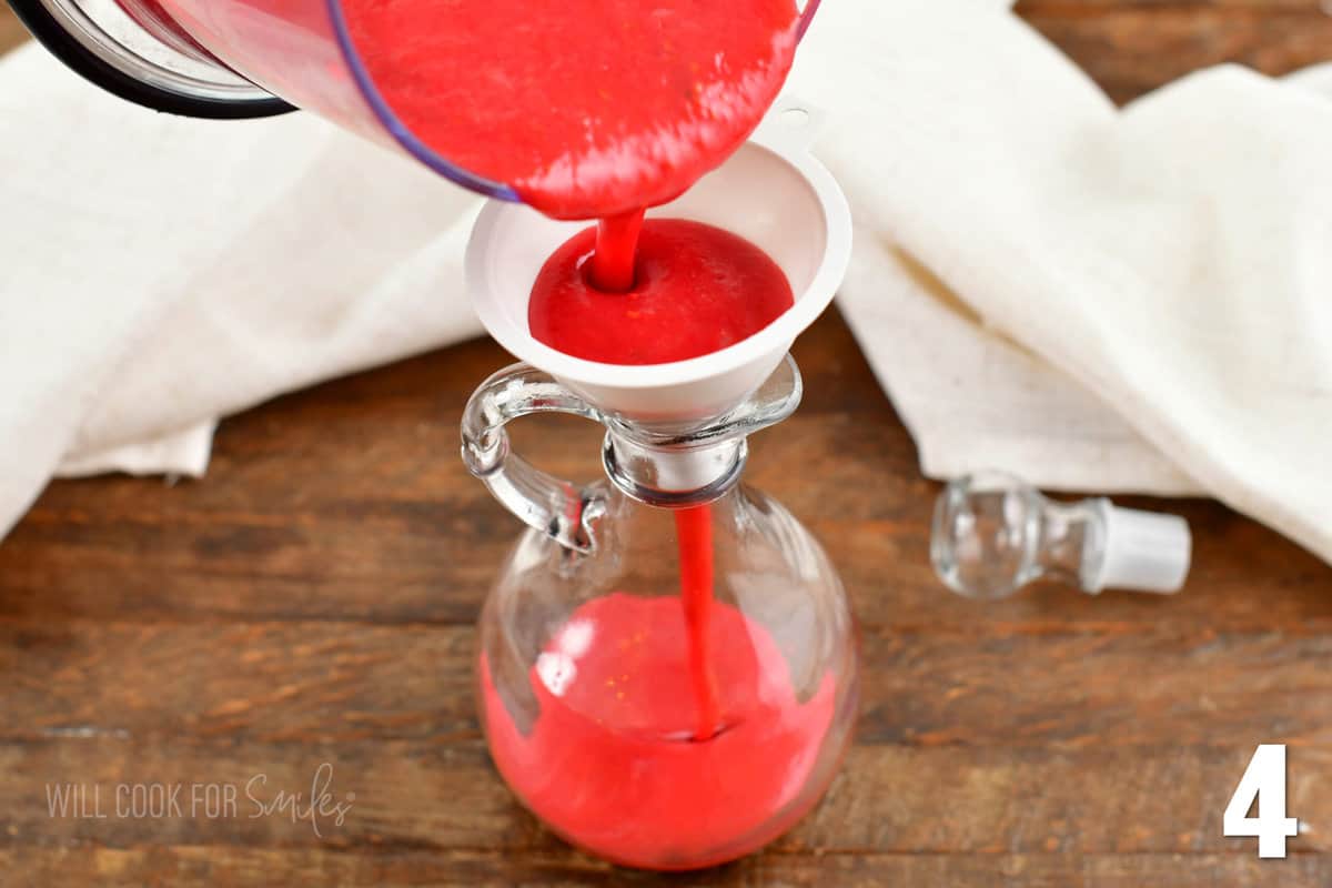 pouring raspberry vinaigrette into the dressing container through the funnel.