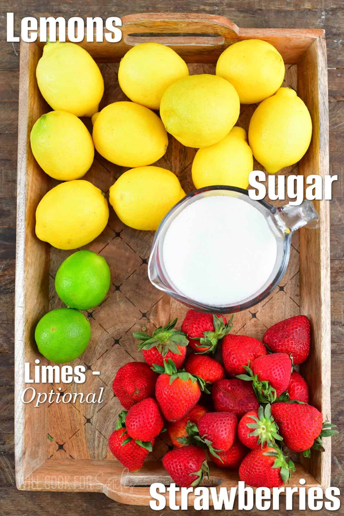ingredients to make strawberry lemonade on a wooden tray.