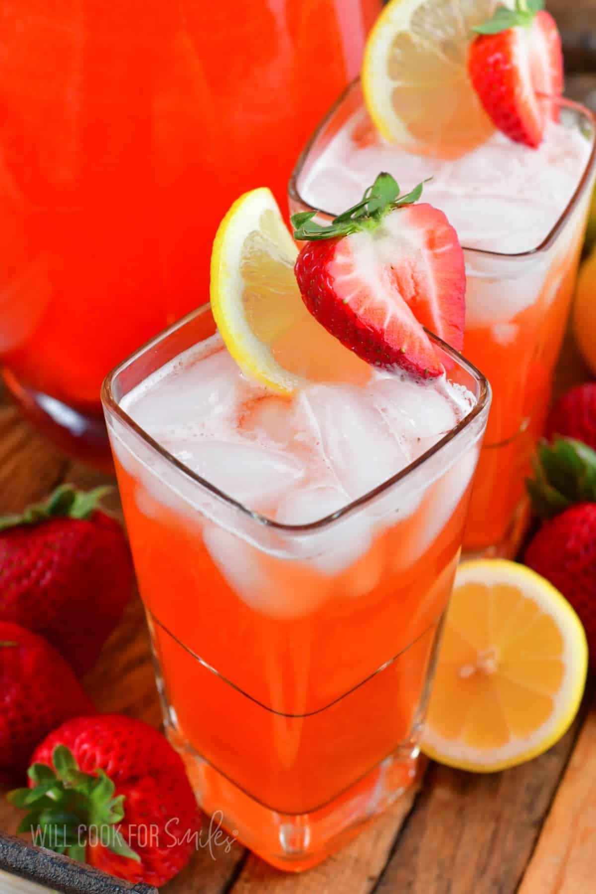 two glasses filled with strawberry lemonade and garnished with lemon slice and stawberry.