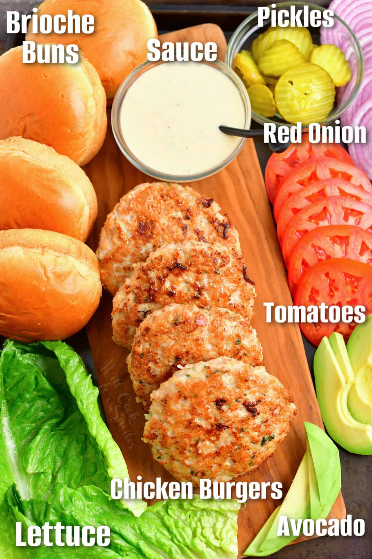 Ingredients to build a chicken burgers labeled in a cutting board.
