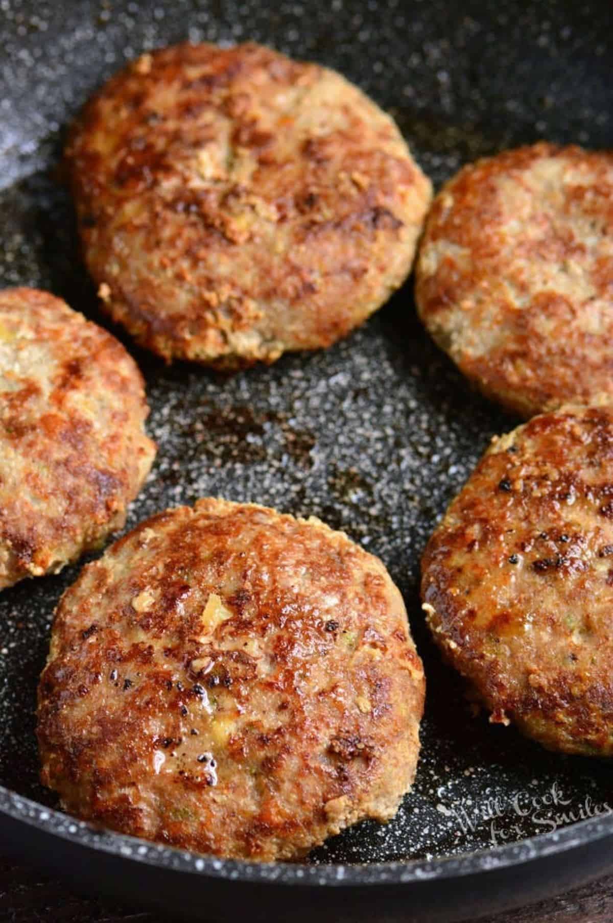 several turkey burgers in a circle in the large cooking pan.