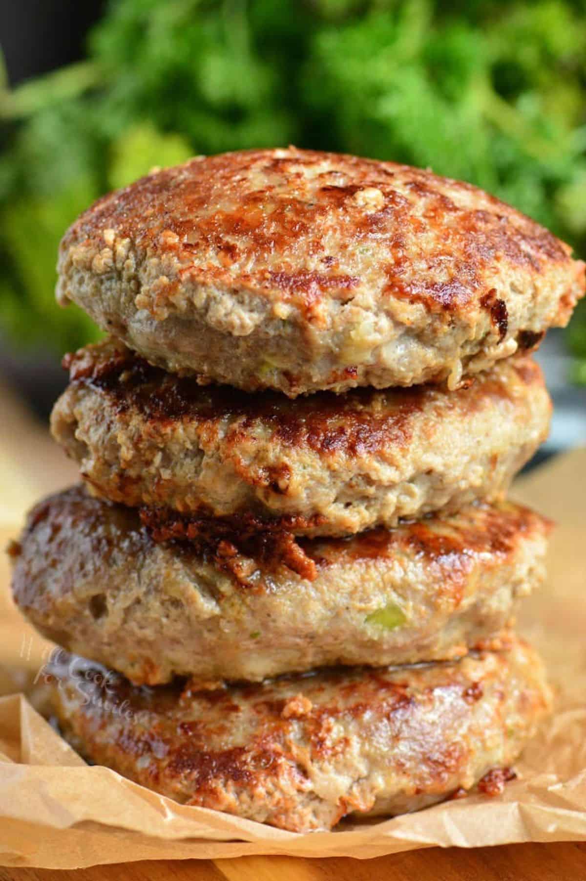 four turkey burgers stacked on top of each other on parchment paper.
