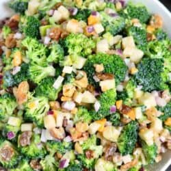 broccoli salad with apples, nuts, and cheese mixed with creamy dressing in a bowl.