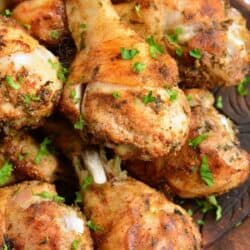 several baked chicken drumsticks with chicken seasoning on a plate.