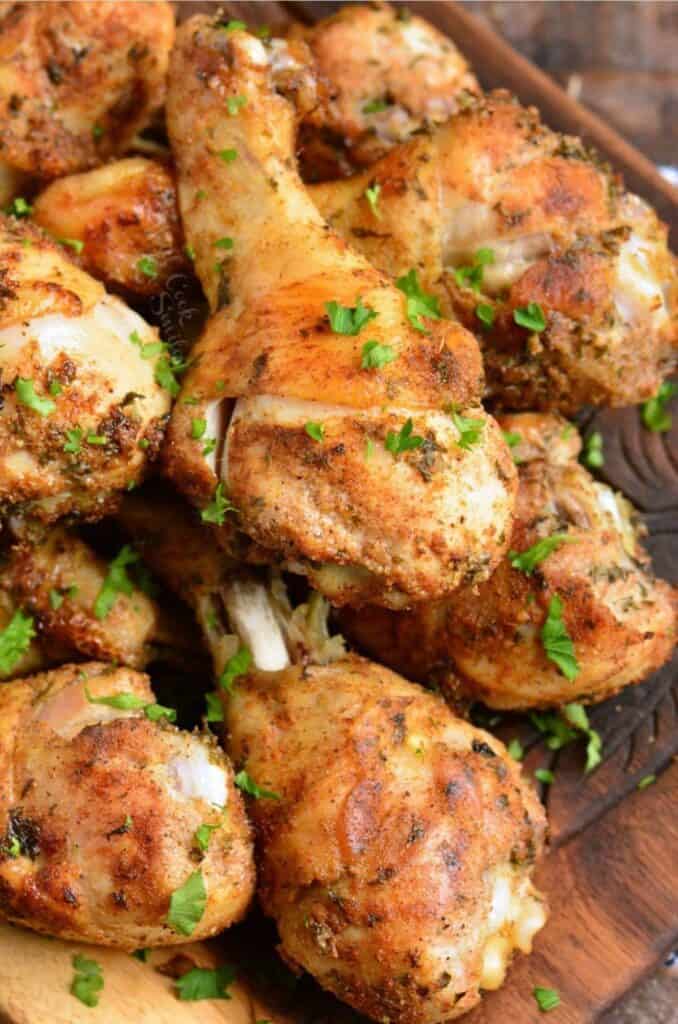 several baked chicken drumsticks with chicken seasoning on a plate.