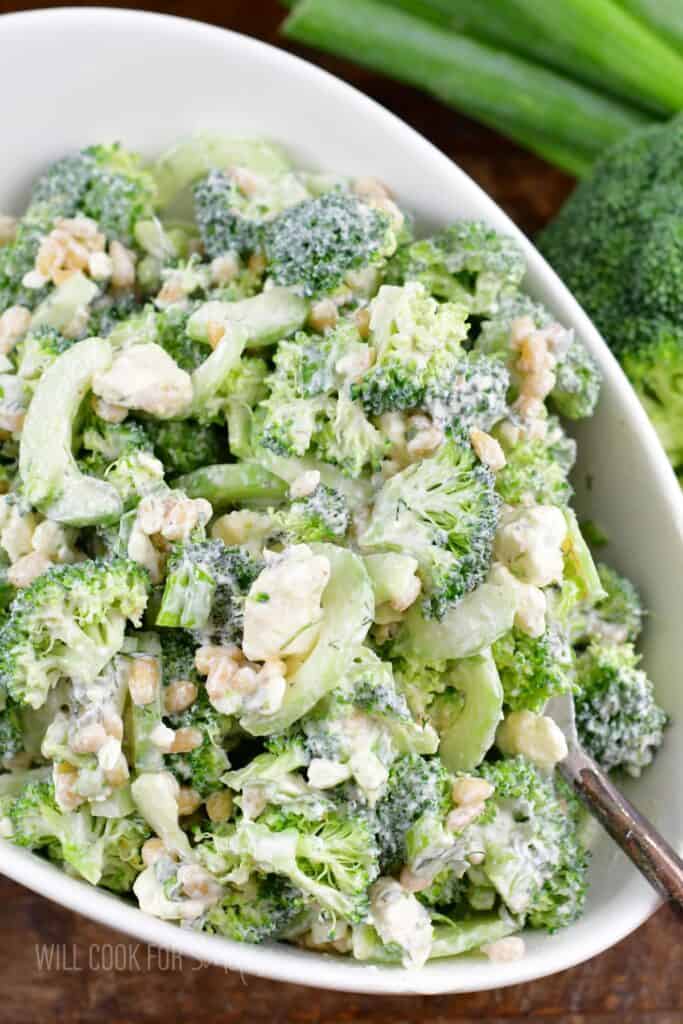 green broccoli salad with cucumber nuts and feta in a white bowl.