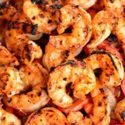 several cajun grilled shrimp on top of onions and peppers