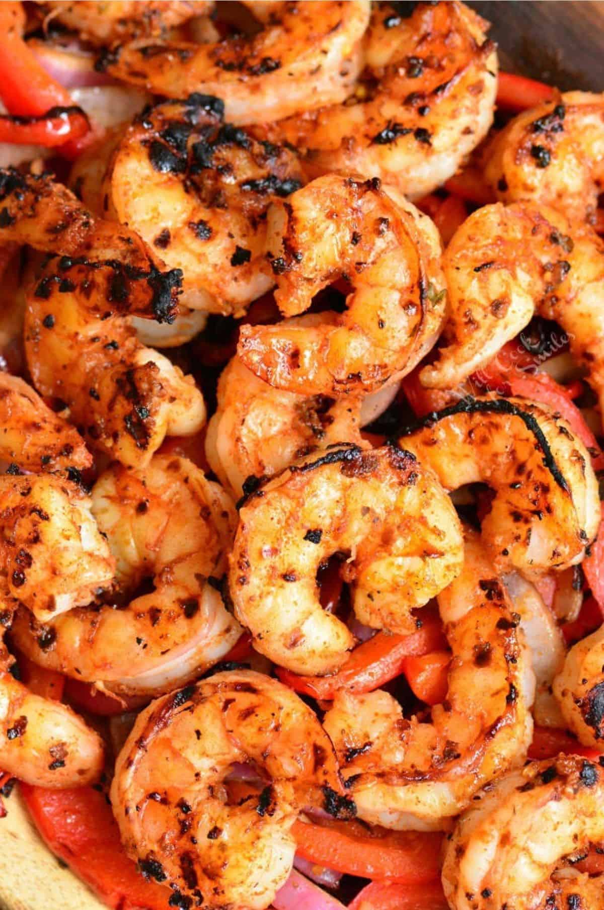 several grilled Cajun shrimp on top of grilled onions and pepper.