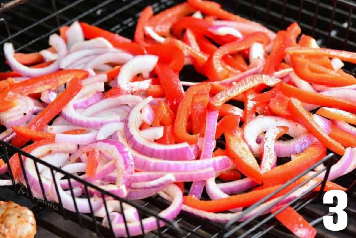 uncooked seasoned sliced onions and peppers in the vegetable basket on the grill.