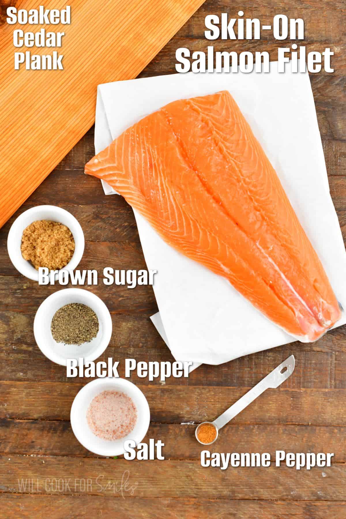 The ingredients for cedar plank salmon are placed on a wooden surface. 