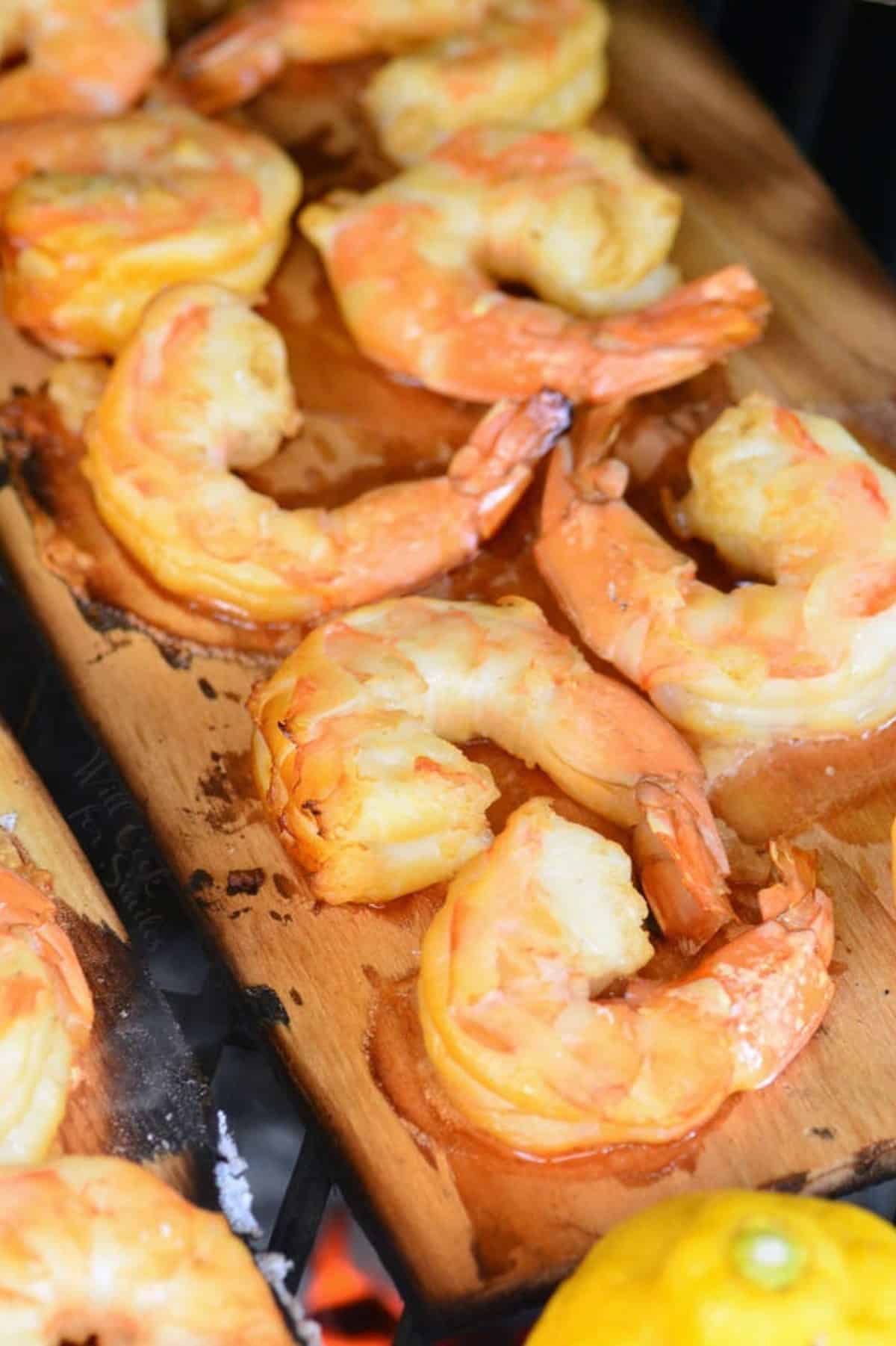 Several cooked shrimp are presented on cedar boards. 