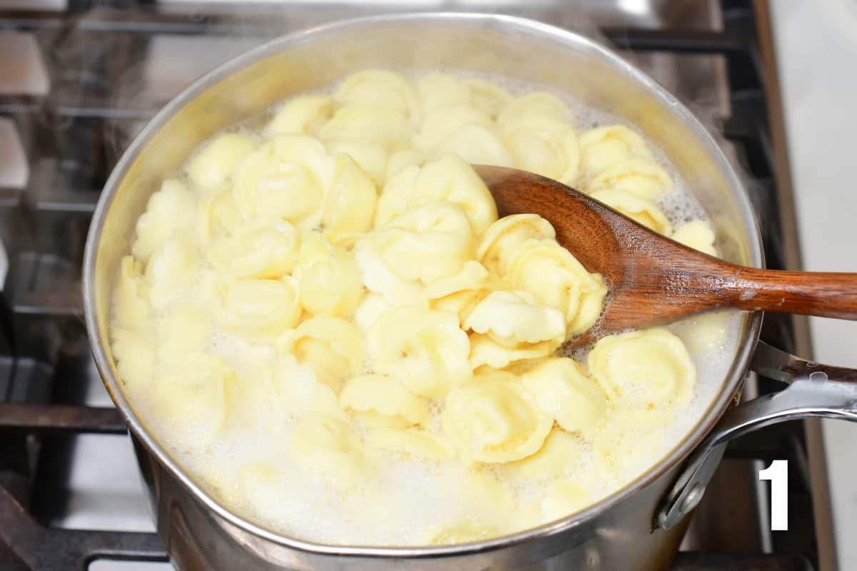 tortellini is being cooked in a large pot and spooning out with a spoon.